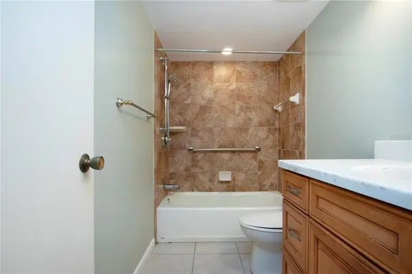 a bathroom with a granite countertop bathtub shower sink vanity and toilet