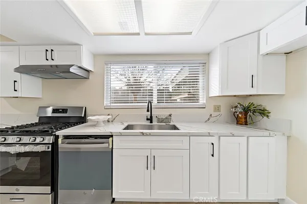 a kitchen with stainless steel appliances granite countertop a sink a stove and cabinets
