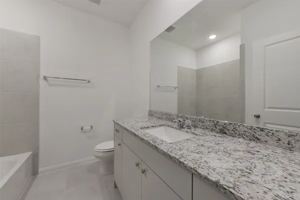 a bathroom with a granite countertop sink a toilet and a shower