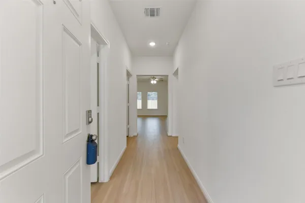 a view of a hallway with wooden floor and a bathroom