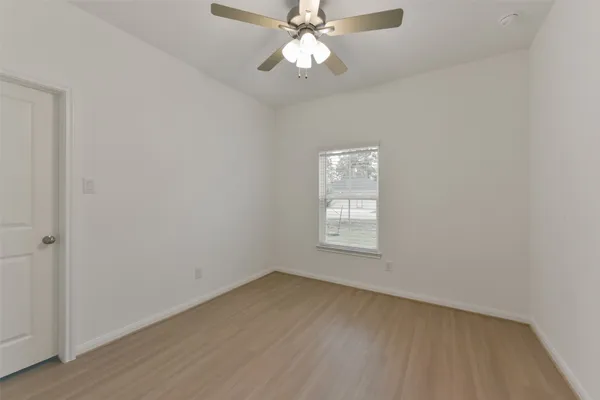 an empty room with a window and a fan
