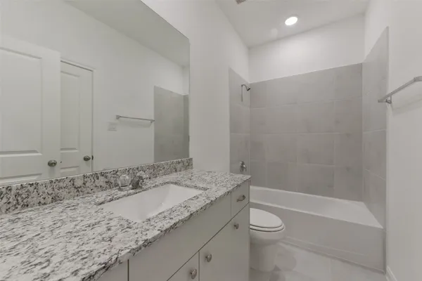 a bathroom with a granite countertop sink a toilet and shower