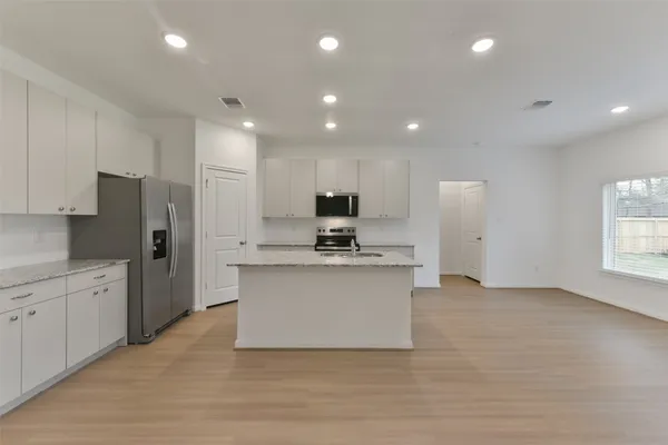 a large kitchen with stainless steel appliances kitchen island granite countertop a stove a sink and a refrigerator