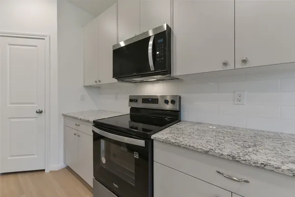 a kitchen with stainless steel appliances granite countertop white cabinets and a stove top oven