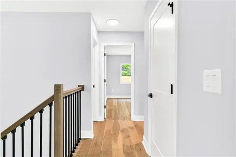 a view of a hallway with wooden floor and staircase