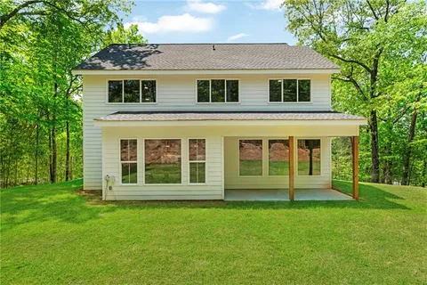 a view of a house with a yard and large trees