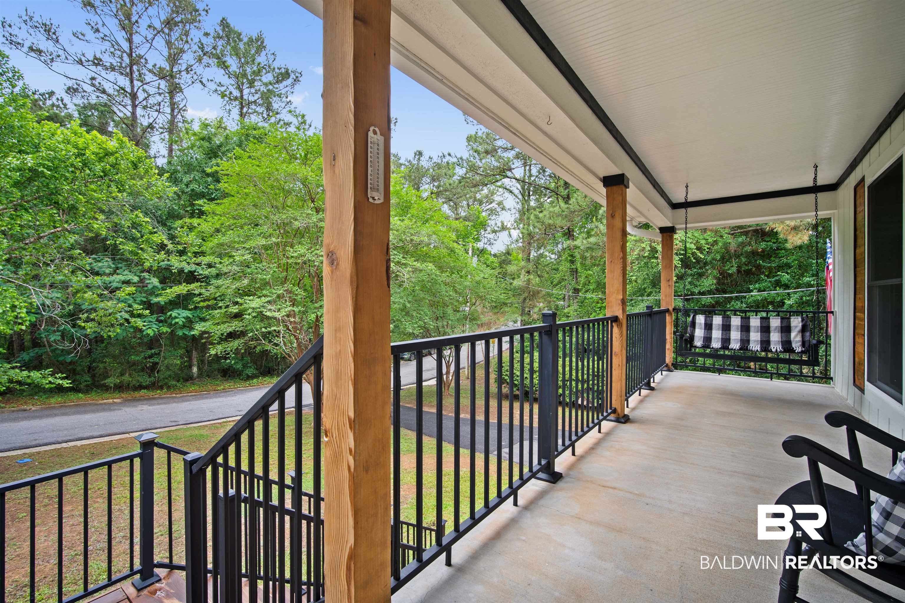 71 Caisson Trace Daphne, AL 36527 - Photo 4 of 36 Expansive covered porch featuring substantial wood columns, black metal railings, and a beadboard ceiling