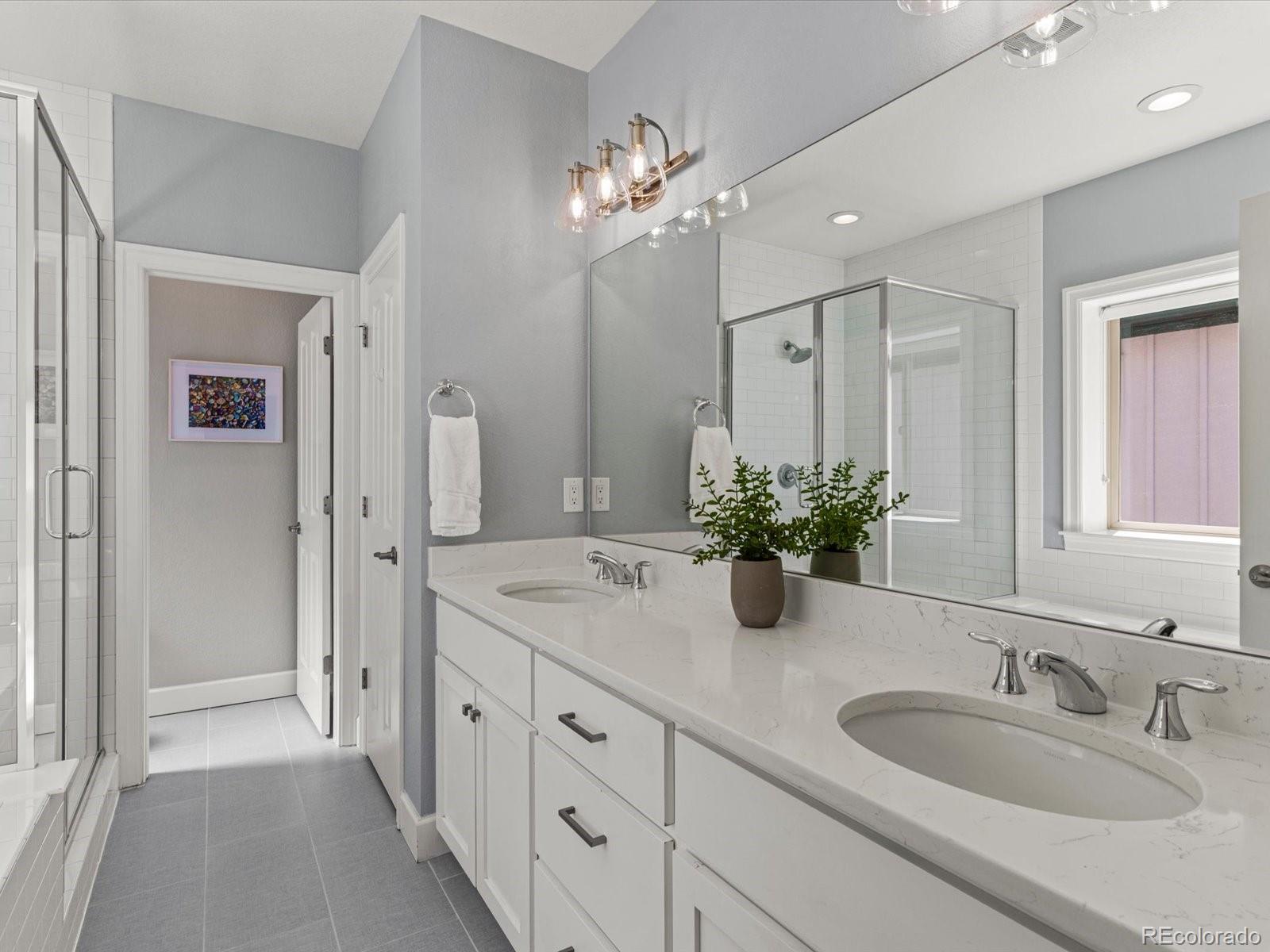 5446 Uinta Way Denver, CO 80238 - Photo 31 of 49 a bathroom with double vanity sinks a vanity a lamp and a mirror