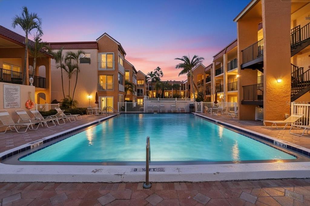 8911 Blind Pass Road, Unit 118 St. Pete Beach, FL 33706 - Photo 4 of 34 a view of a swimming pool with a lounge chairs