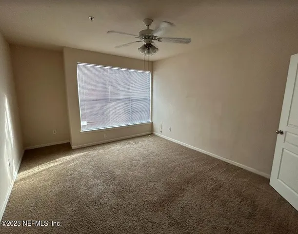 an empty room with a ceiling fan and a window