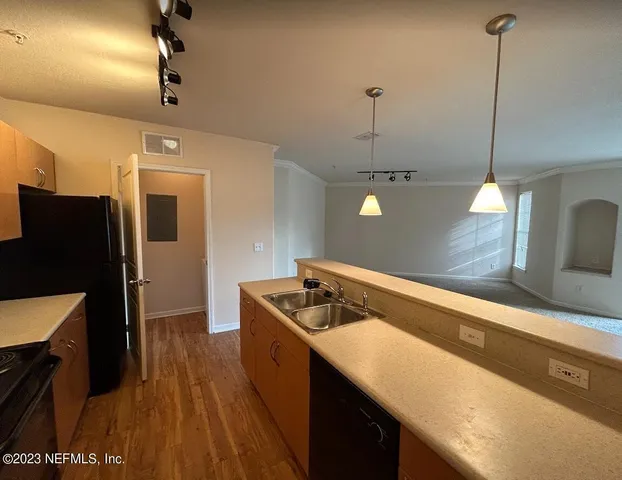 a kitchen with a sink a refrigerator and wooden floor