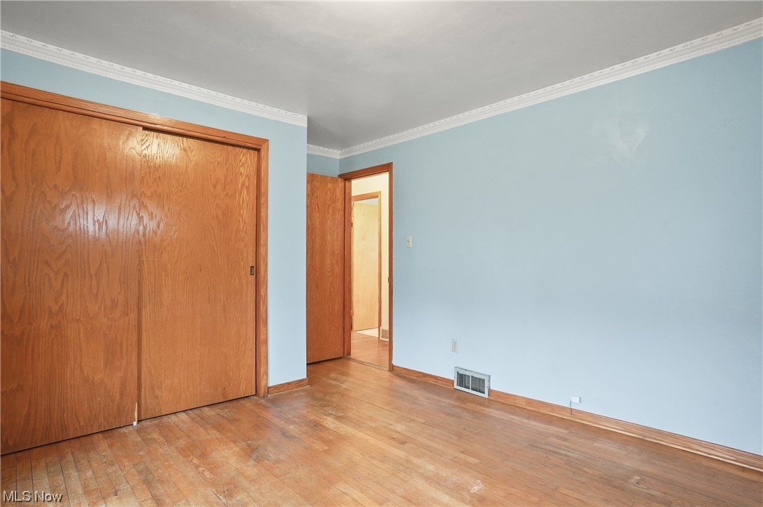 7380 Tallmadge Road Rootstown, OH 44272 - Photo 12 of 23 Unfurnished bedroom featuring ornamental molding, light hardwood / wood-style flooring, and a closet