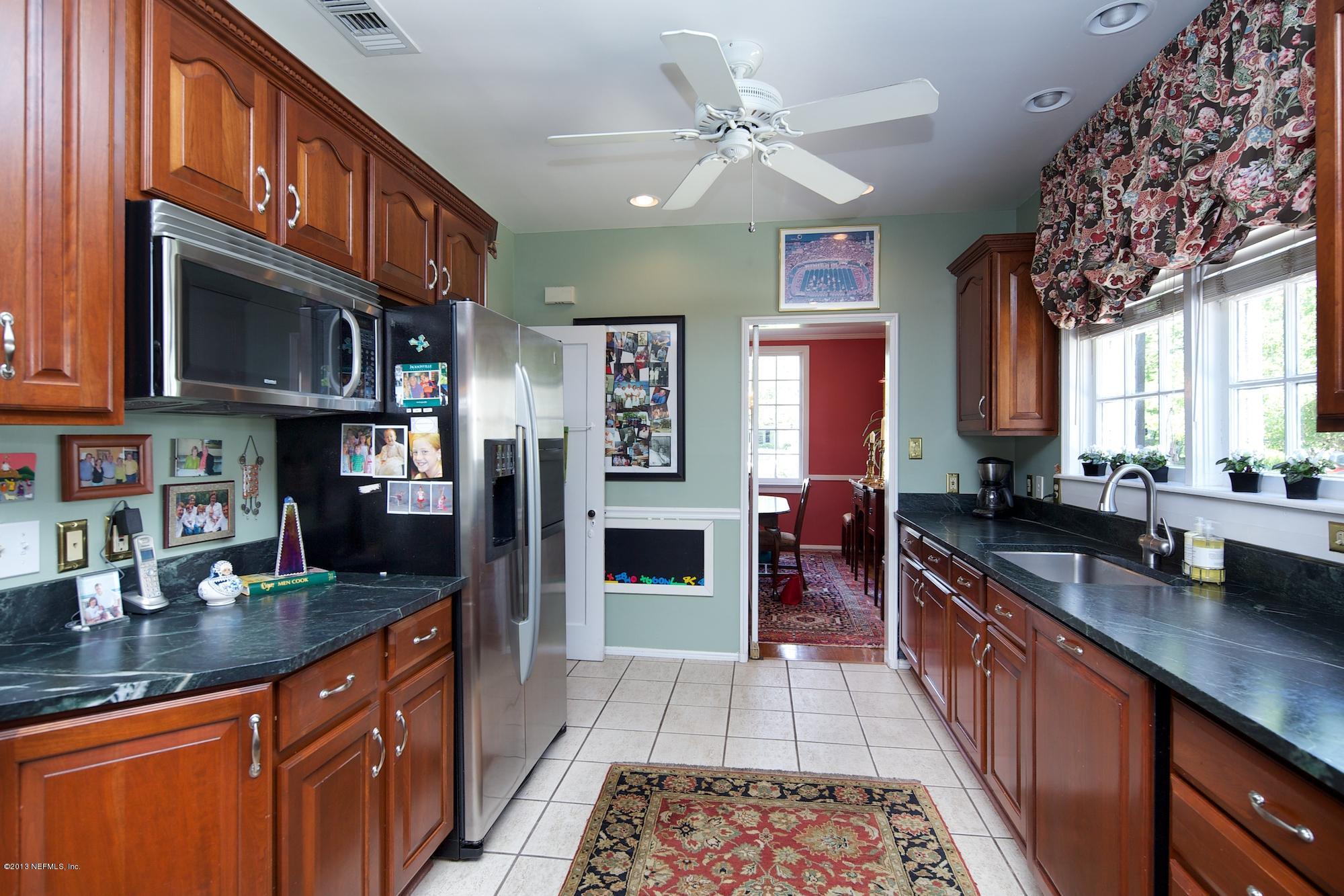 1138 Greenridge Road Jacksonville, FL 32207 - Photo 11 of 36 a kitchen with stainless steel appliances granite countertop a refrigerator a stove and a sink with wooden cabinets