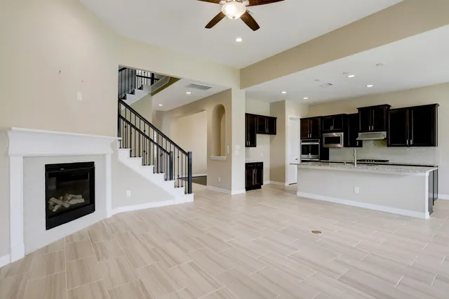a view of an empty room with wooden floor and a kitchen