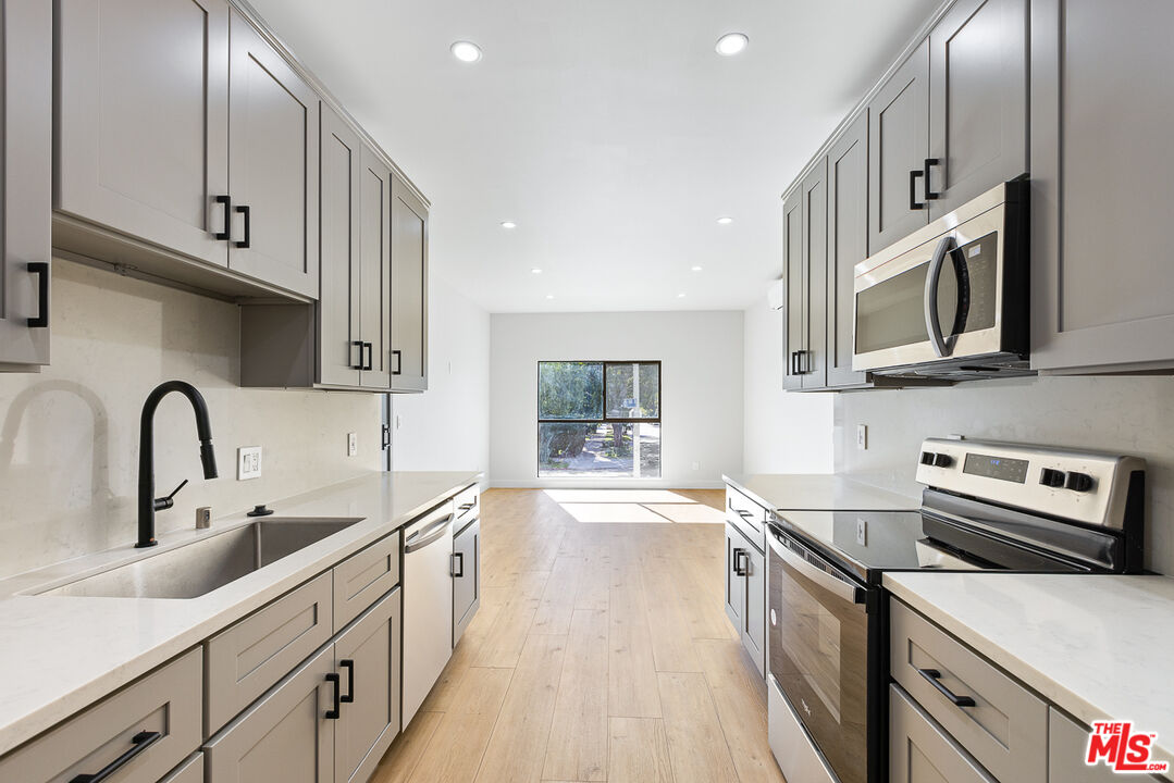 a kitchen with stainless steel appliances granite countertop a sink a stove and cabinets