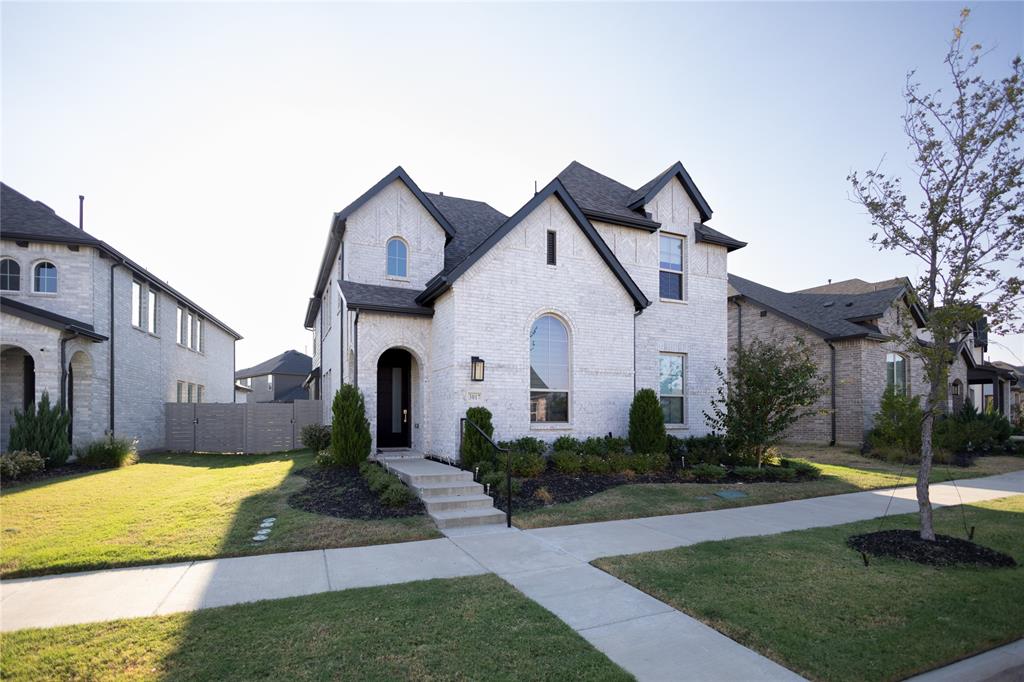 3017 Andorra Road McKinney, TX 75071 - Photo 2 of 40 White brick exterior with dark trim, arched entry, arched window, established landscaping, and concrete walkway