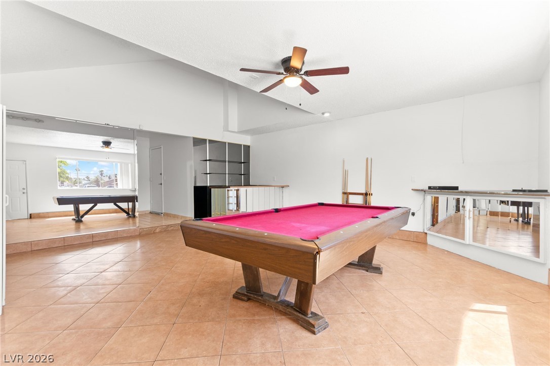4430 Cranbrook Way Las Vegas, NV 89103 - Photo 29 of 50 A spacious recreation room featuring a billiard table, reflective wall accents, and an overhead ceiling fan for comfort.