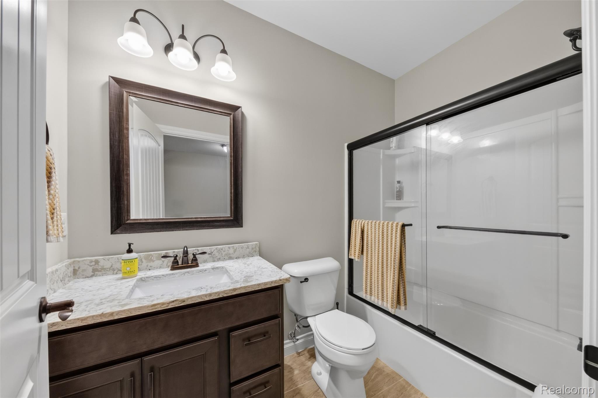 2531 Walnut View Drive Howell, MI 48855 - Photo 29 of 34 Bathroom featuring a dark wood-finish vanity with a light-toned countertop, an undermount sink, and a framed mirror