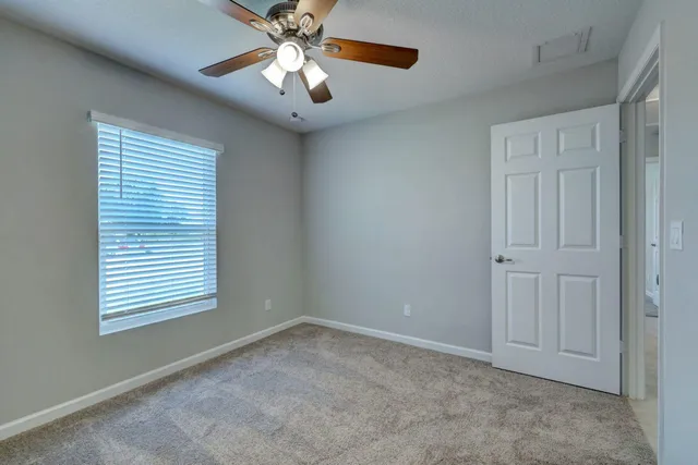 an empty room with windows and ceiling fan