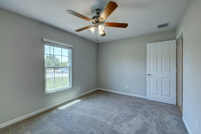 an empty room with a chandelier fan and closet area