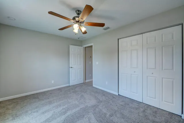 an empty room with a chandelier fan and windows