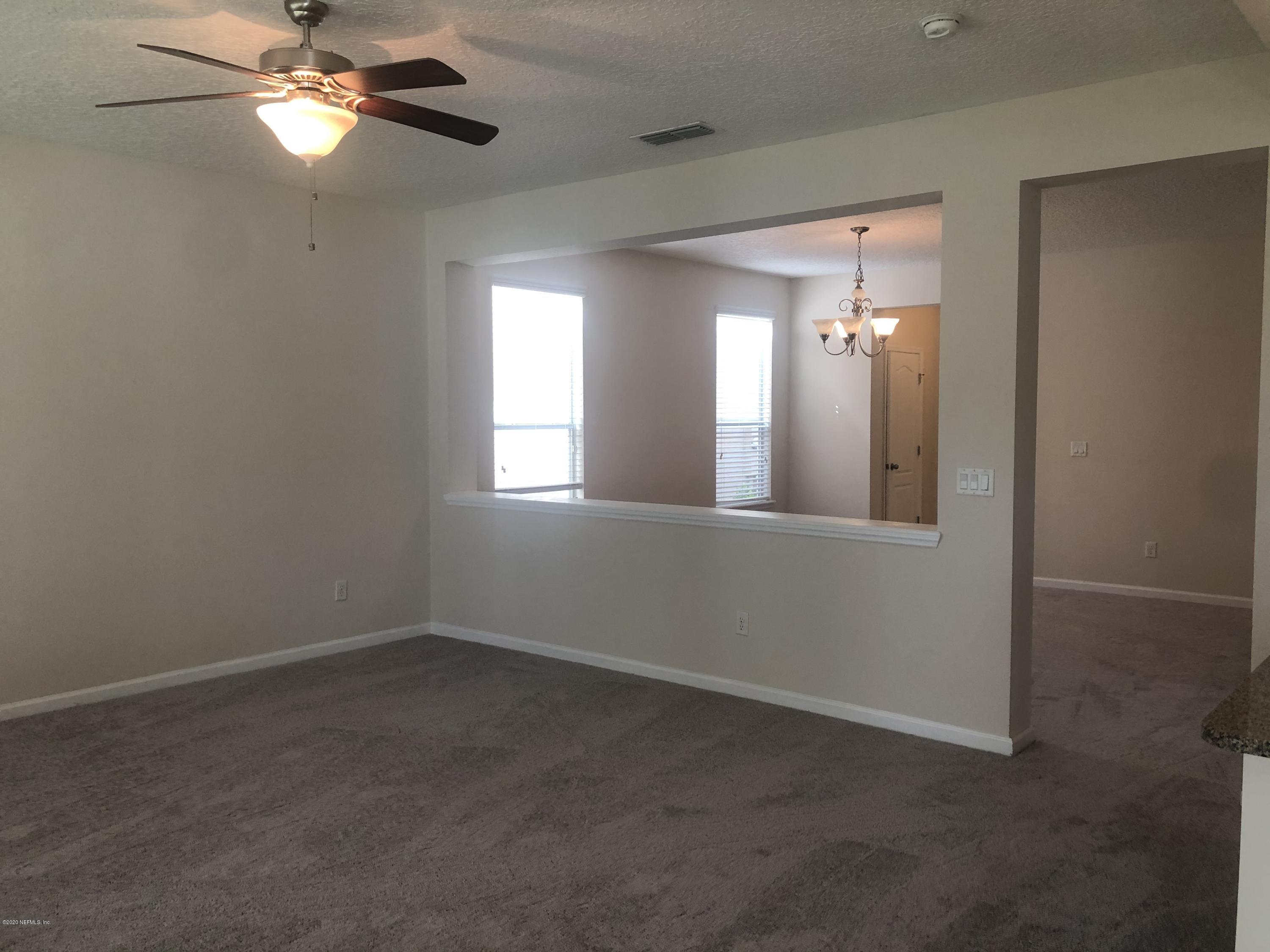 3782 Chasing Falls Road Orange Park, FL 32065 - Photo 4 of 22 an empty room with chandelier fan and windows