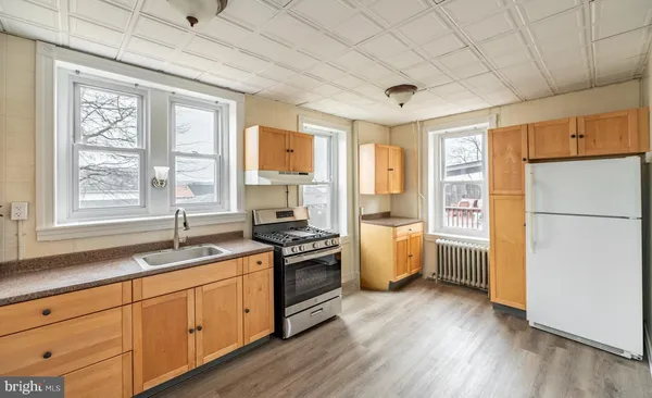 a kitchen with a refrigerator a sink dishwasher stove and wooden cabinets