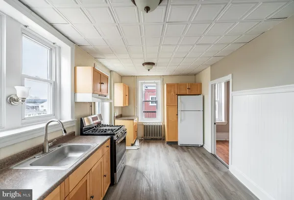 a kitchen with a sink appliances cabinets and a large window