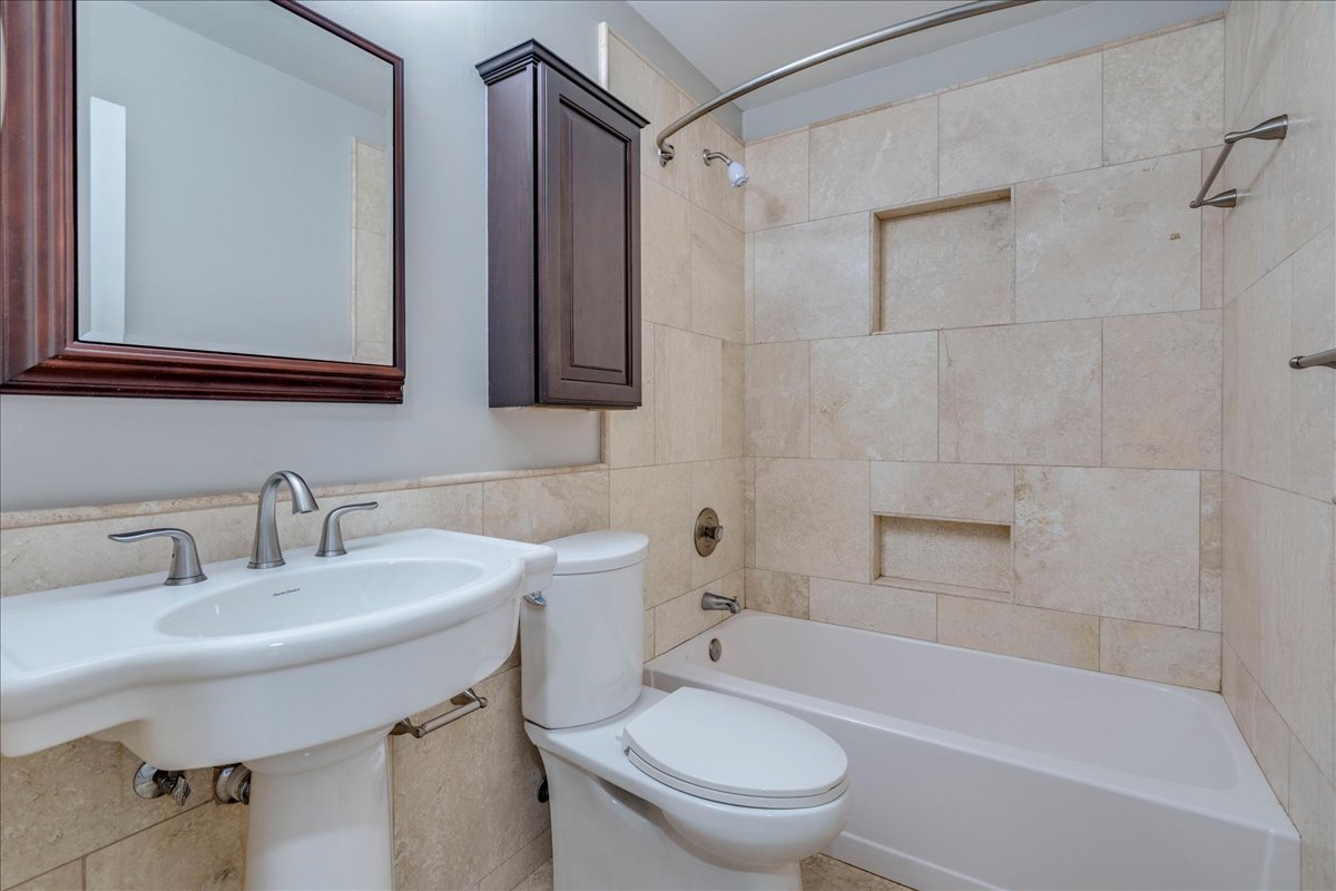 6530 Needham Lane Austin, TX 78739 - Photo 23 of 29 A well-appointed bathroom features a pedestal sink, tiled shower, and convenient recessed shelves.