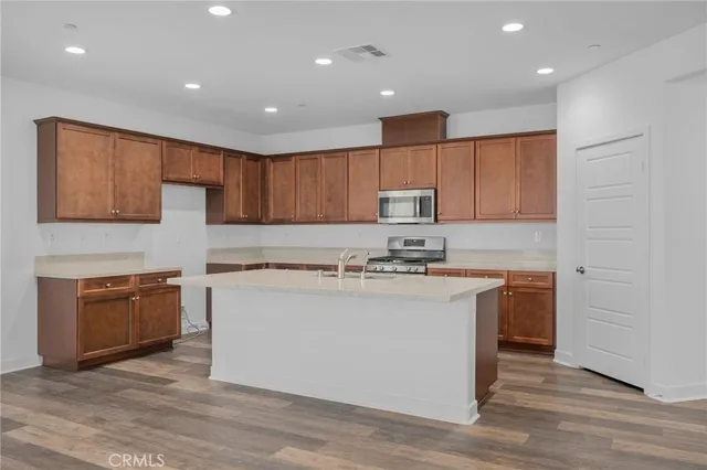 a kitchen with stainless steel appliances granite countertop a stove top oven a sink and a refrigerator with wooden floor