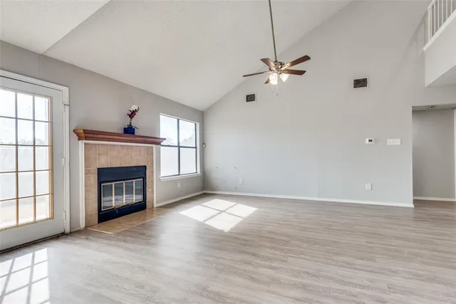 a view of an empty room with chandelier fan and fire place