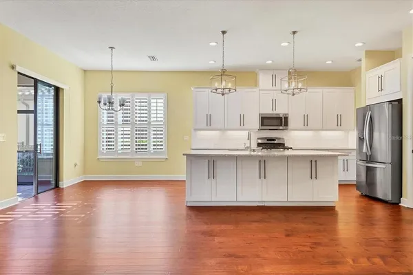a kitchen with stainless steel appliances granite countertop a stove a sink a refrigerator and white cabinets with wooden floor