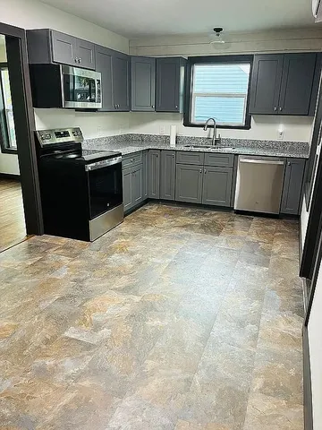 a kitchen with stainless steel appliances granite countertop a stove top oven a sink dishwasher and a refrigerator