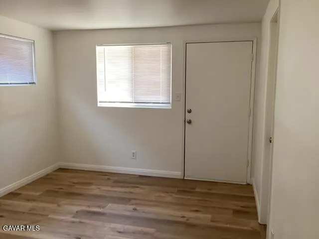 a view of an empty room with wooden floor and a window