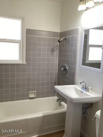 a bathroom with a sink a bathtub and next to a window
