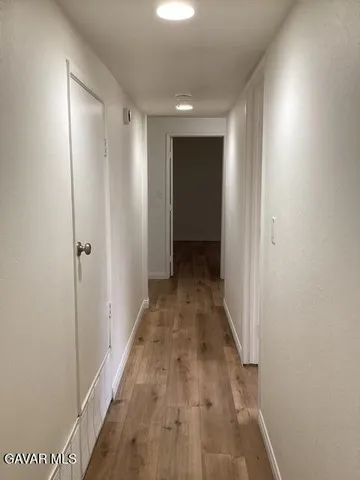a view of a hallway with wooden floor and closet