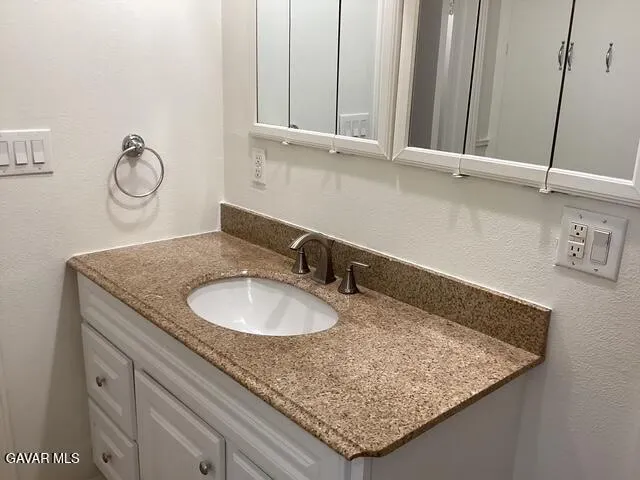 a bathroom with a granite countertop sink and a mirror