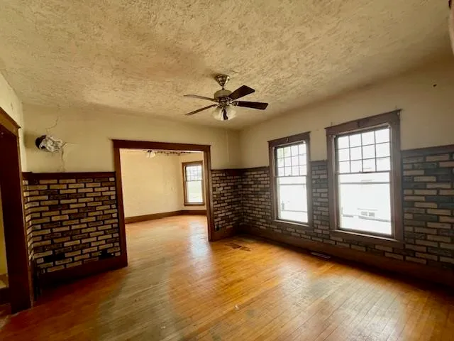an empty room with windows and ceiling fan