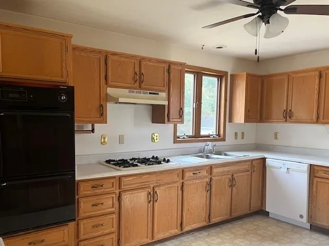 a kitchen with granite countertop a sink cabinets stainless steel appliances and a window