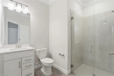 a bathroom with a toilet a sink a mirror a shower and vanity