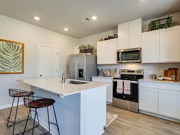 a kitchen with stainless steel appliances a stove a sink a microwave a refrigerator and cabinets