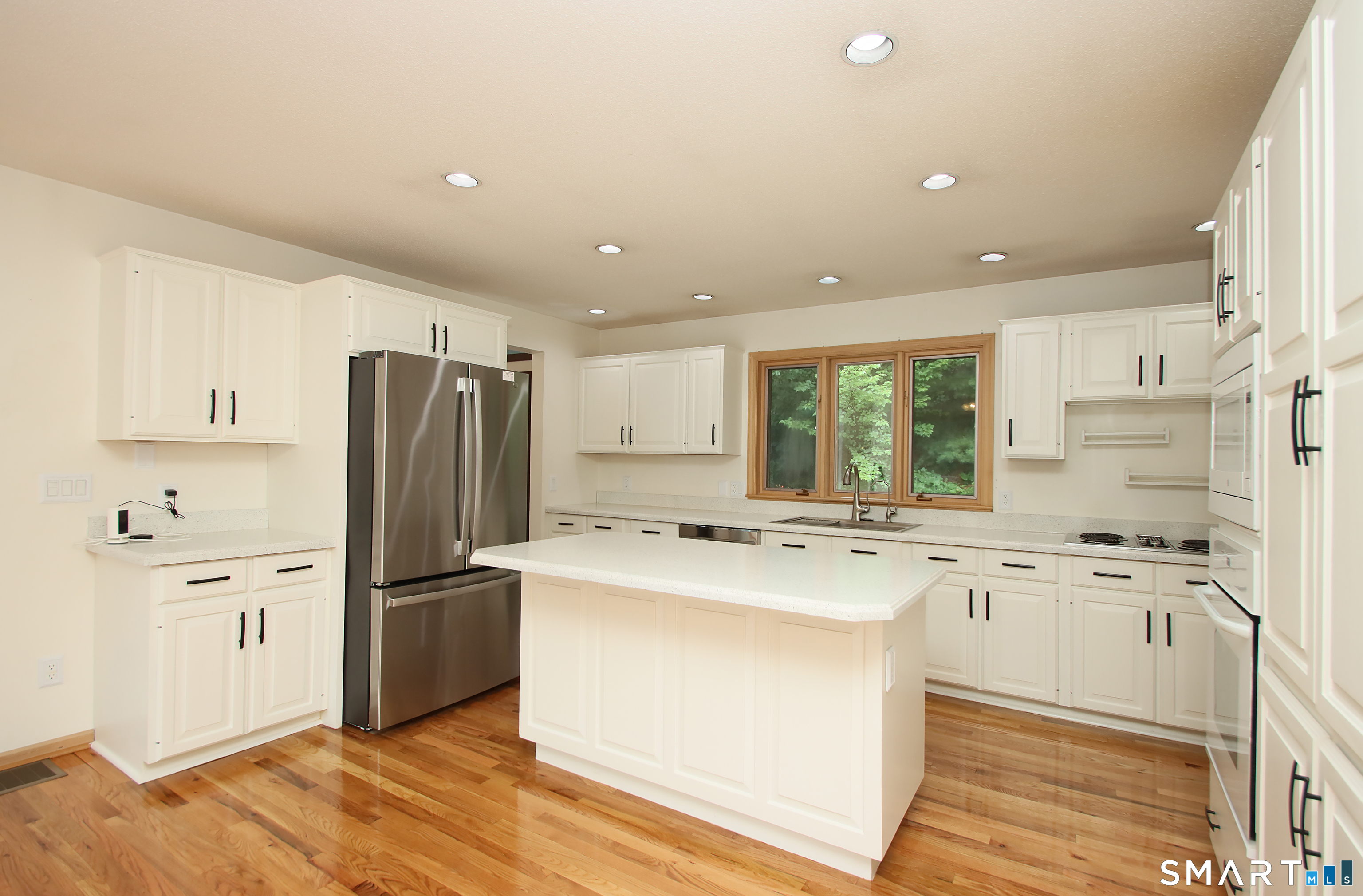 352 Center Street Wolcott, CT 06716 - Photo 10 of 40 a kitchen with a refrigerator a stove and white cabinets with wooden floor