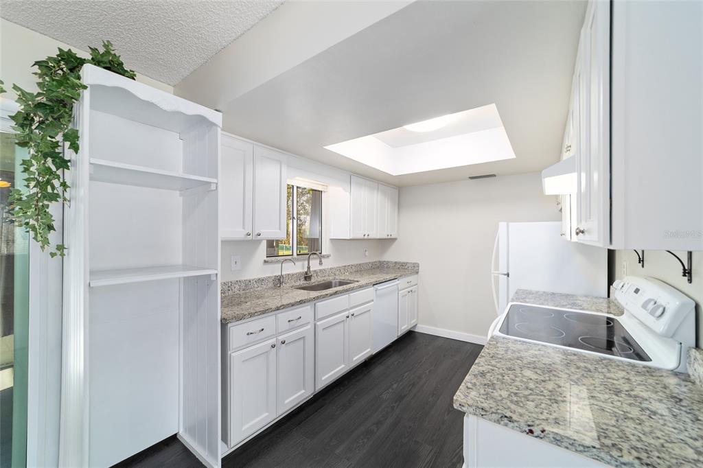 8329 Southwest 105th Place Ocala, FL 34481 - Photo 12 of 39 a kitchen with a sink dishwasher a stove and white cabinets with wooden floor