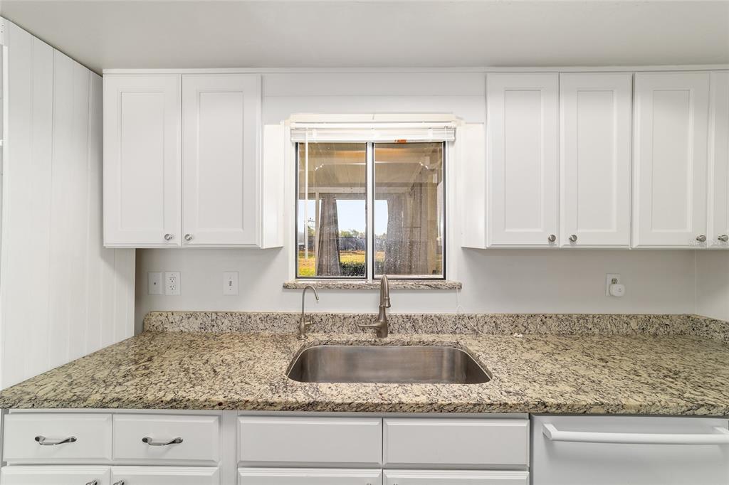 8329 Southwest 105th Place Ocala, FL 34481 - Photo 13 of 39 a kitchen with granite countertop a sink and white cabinets