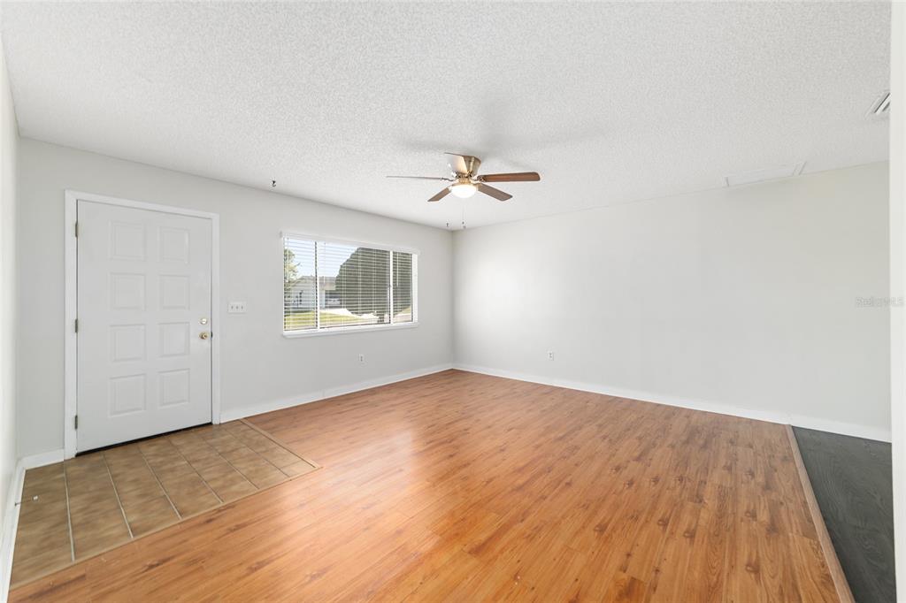 8329 Southwest 105th Place Ocala, FL 34481 - Photo 6 of 39 an empty room with wooden floor chandelier fan and windows