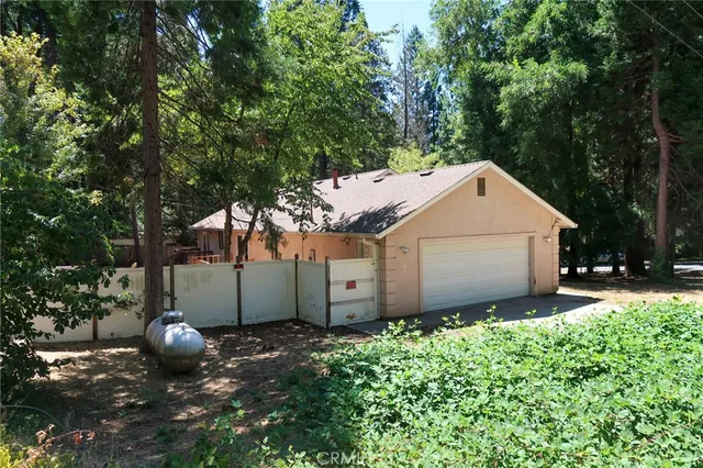 a view of a small house with large tree and wooden fence