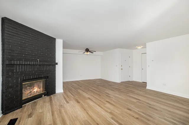 a view of empty room with wooden floor and fireplace