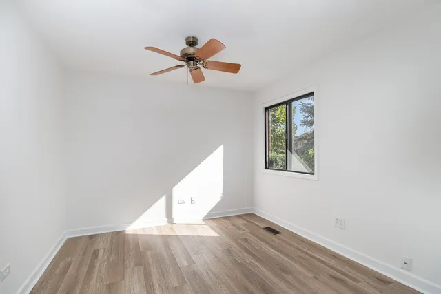 a view of empty room with wooden floor and fan