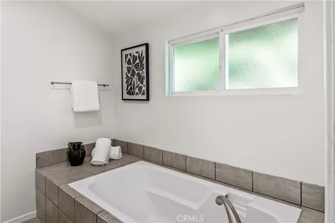 a backyard of a house with table and chairs potted plants and large tree