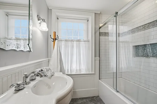 a bathroom with a sink and mirror with bathtub